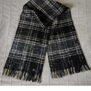 Svart/beige/grå vit rutig halsduk - Made in France  - Sjukt snygg svart/grå/beige/vit rutig lite lurvig halsduk med fransar Made in France. Ca 150 cm lång exkl. fransarna och 30 cm bred. 73% Akryl 14% polyester 13% ull. Bara använd någon enstaka gång. 