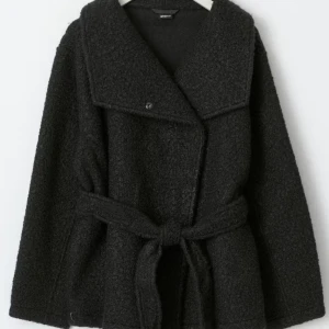Svart teddyjacka med bälte från Gina Tricot - Säljer en svart teddyjacka från Gina Tricot med bred krage och knytbälte i midjan. Jackan har lång ärm och en oversized passform. Passar perfekt nu till vintern. Storlek s/m, priset kan diskuteras.