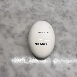 Chanel La Crème Main handkräm - Chanel La Crème Main är en lyxig handkräm i en snygg, äggformad vit förpackning med svart text. Perfekt att ha med sig i väskan. Endast använd några få gånger, ordinarie pris 724 🩷