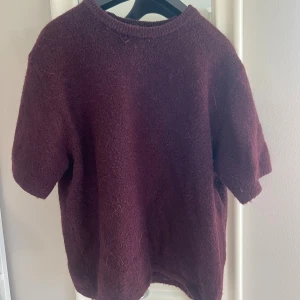 Vinröd stickad tröja Gina Tricot - Mysig vinröd stickad tröja från Gina Tricot med korta ärmar och rund halsringning. Tröjan har en fluffig känsla och är perfekt för lager-på-lager. Passar dig som gillar en enkel men trendig look.