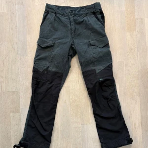 Klättermusen byxor Gleipner Svarta - Grymma svarta vandrar byxor från Klättermusen, modell Gleipner. Byxorna har flera stora fickor med lock, förstärkta partier på knäna och justerbara benslut. Perfekta för outdoor och äventyr. Materialet är slitstarkt och känns robust. Snyggt slitna. Inga defekter.  Nypris 3000