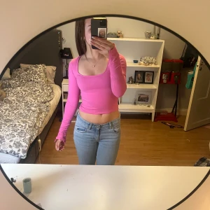 Rosa croppad långärmad topp - Säljer en rosa croppad topp med lång ärm och fyrkantig ringning. Toppen är figurnära och har en enkel, stilren design utan mönster eller detaljer. Perfekt att matcha med jeans eller kjol för en snygg look. Använd 2 gången då jag inte gillar färgen rosa 💕