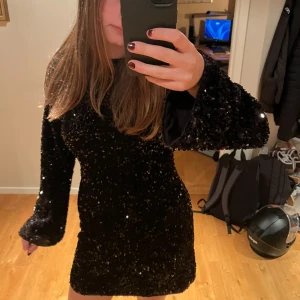 Svart glittrig paljettklänning - Säljer en superfin svart kort klänning med glittriga paljetter över hela tyget. Klänningen har långärmade ärmar och en figurnära passform som ger en snygg look. Perfekt nu till nyår! Den är endast använd 2 gånger, alltså är den i väldigt bra skick💕 Den har storlek S men jag skulle säga att den även passar M