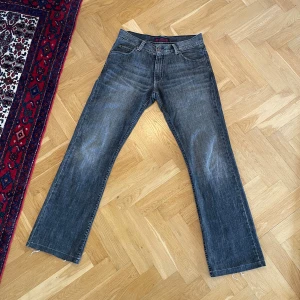 Washed black jeans från Redwood - Snygga tvättade svarta jeans från RDWD Jeans med nästan bootcut passform och klassisk femficksdesign. Jeansen har en mörk tvätt med slitningar och detaljerade sömmar på bakfickorna. Uppsydda så den sanna längden är 32-33