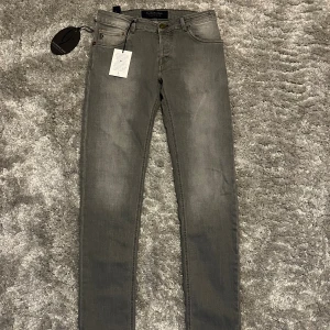 Grå jeans från Handpicked, slim fit - Aldrig använda jeans från Handpicked med klassisk femficksdesign och diskreta slitningar. Jeansen har slim passform och raka ben, tillverkade i mjukt bomullsmaterial med en touch av stretch för extra komfort. Perfekta för dig som gillar stilrena och moderna jeans.