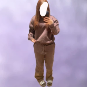 Brunt Mjukis set - Mysiga bruna mjukisbyxor med snörning i midjan och en hoodie. Perfekta för chill dagar eller när du bara vill vara bekväm. Byxorna och hoodien har en loose passform och är tillverkade i mjukt material.