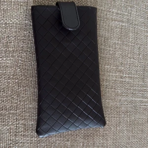 Svart skinnfodral från Bottega Veneta - Snyggt brun fodral från Bottega Veneta i flätat skinn med elegant och stilren design. Perfekt för att förvara glasögon eller småprylar. Fodralet har ett mjukt innerfoder och stängs med en smidig flärp. Kommer med putsduk i matchande färg.