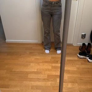 Grå bootcut jeans från Gina tricot - Säljer ett par grå jeans från Gina tricot i bootcut-modell. De har medel hög midja och klassisk femficksdesign. Jeansen är i ett mjukt denimtyg och har en snygg, lite tvättad look. Perfekta för dig som gillar en avslappnad men trendig stil.