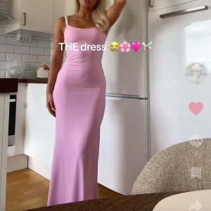 Ljusrosa långklänning med smala axelband - Supersnygg ljusrosa långklänning med smala axelband och figurnära passform. Klänningen har en enkel, stilren design och är tillverkad i ett mjukt, stretchigt material som sitter skönt på kroppen. Perfekt för dig som gillar minimalistisk och trendig stil. Från Bershka storlekslapp bortklippt vid rygg men finns en på insida höft