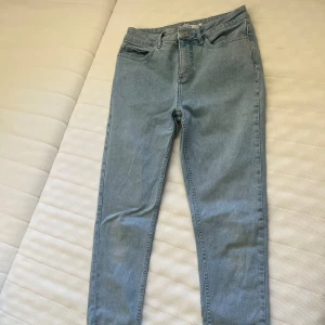 Ljusblå skinny jeans från NA-KD - Snygga ljusblå skinny jeans från NA-KD med hög midja och råa, slitna benslut. Klassisk femficksmodell i mjuk denim med dragkedja och knapp framtill. Perfekta för en avslappnad och trendig look.