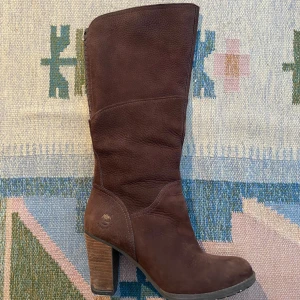 Bruna mockastövlar från Timberland - Snygga bruna stövlar från Timberland i mjuk mocka med rund tå och rejäl klack. Stövlarna har en klassisk siluett och träfärgad klack som ger en cool touch. Perfekta till höstens outfits och funkar lika bra till jeans som till klänning. Små i storleken :) 