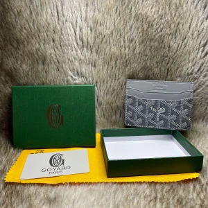 Grå korthållare i skinn - Snygg korthållare i grått skinn med klassiskt mönster och flera kortfack. Den har ikoniska tryck i vitt och svart och levereras med originalask och dustbag. Perfekt för dig som vill ha en stilren och lyxig accessoar i fickan.