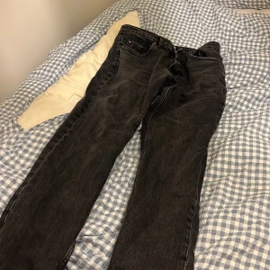 Svarta raka jeans från Pull&Bear - Säljer ett par svarta jeans från Pull&Bear med klassisk femficksdesign och raka ben. Jeansen har en snygg tvättad look, dragkedja och knapp framtill samt detaljer i kopparfärg. Perfekta för en avslappnad och stilren vibe.