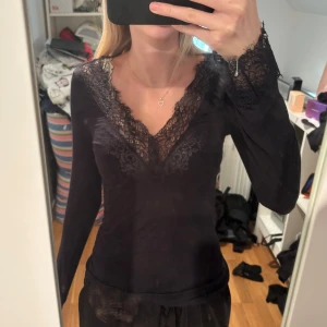 Svart långärmad spetsblus från intimissimi - Säljer en svart långärmad topp från intimissimi med snygga spetsdetaljer vid v-ringad hals och ärmslut🩷
