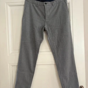 Grå kostymbyxor från Zara Man - Snygga grå kostymbyxor från Zara Man med klassisk rak passform. Byxorna har bälteshällor, framfickor och bakfickor med knapp. Perfekta för en clean och stilren look. Materialet känns mjukt och är troligtvis bomull eller polyesterblandning.