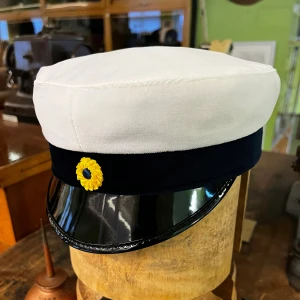 Klassisk studentmössa (Lunda) 52-63 - Klassisk studentmössa med vit mösskulle i bomull, blått band och blank svart skärm. Framtill sitter en klassisk kokard. Insidan har det klassiska foder i blått och gult. Lunda-modell. Finns storlekar från 52–63. Limiterat lager.