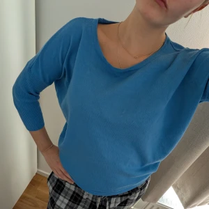 Blå stickad tröja med rund hals - Mysig blå stickad tröja med rundad halsringning och ribbade muddar på ärmarna. Tröjan har en avslappnad passform och är perfekt för lager-på-lager. Enkel och stilren design som funkar till det mesta.