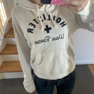 Vit hoodie från Hollister - Vit hoodie från Hollister med svart tryck. Supermysig nu med kallare väder!