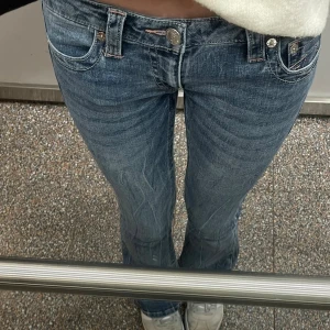 True Religion blå bootcut jeans - Jättefina True religon jeans med rosa detaljer. Använda men i fint skick har en liten slitning längst ner på ena benet men inget man tänker på! 