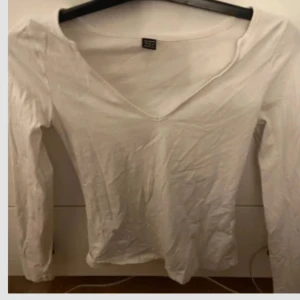 Vit långärmad v-ringad tröja - En stilren vit långärmad tröja från SHEIN med v-ringad hals. Tröjan är i mjuk bomull och har en klassisk passform som funkar till många olika outfits. Perfekt basplagg för garderoben.