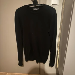 Svart långärmad tröja Dressmann S - En stilren svart långärmad tröja från Dressmann i storlek S. Tröjan är tillverkad i mjuk bomull och har en klassisk rund halsringning. Perfekt för dig som gillar en enkel och clean look.