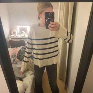 Randig vit och svart stickad tröja - Säljer en oversized stickad tröja i vitt med svarta horisontella ränder. Tröjan har lång ärm och en avslappnad passform, perfekt för mysiga dagar. Enkel och stilren design som funkar till det mesta.