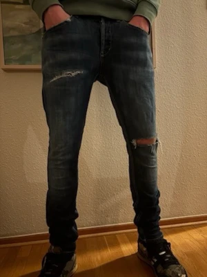 Dondup Jeans W31 – Exklusiva, Slitna Detaljer - Säljer ett par exklusiva Dondup jeans i storlek W31 med flertal slitningar. Jeansens slitna look gör dem unika och välanvända, vilket också reflekteras i prislappen.  Mått (se sista bilden): 	•	A: 38 cm 	•	B: 74 cm 	•	C: 19 cm 	•	D: 15 cm  Perfekta för dig som vill ha ett par stilrena, välanvända lyxjeans med karaktär. ⚜️