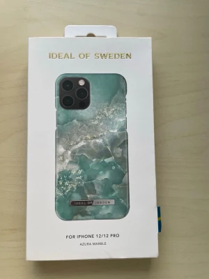 Azura Marble skal iPhone 12/12 Pro - Snyggt mobilskal från iDeal of Sweden i marmor-inspirerat mönster med turkosa och vita nyanser. Passar iPhone 12/12 Pro. Skalet är gjort i hårdplast och har en lyxig känsla med gulddetalj vid loggan.