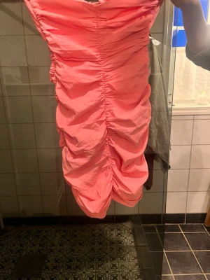Rosa klänning från Zara  - Supersnygg rosa kortklänning med rynkade detaljer längs hela klänningen. Klänningen har snörning upptill och är ärmlös, vilket ger en trendig och ungdomlig look. Perfekt för sommarens alla tillfällen.