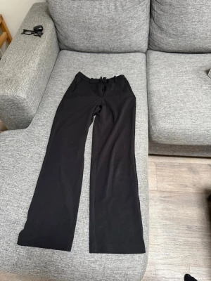 Svarta raka kostymbyxor  - Svarta mjukisbyxor med raka, vida ben och dragsko i midjan. Byxorna har en enkel och stilren design utan synliga loggor eller detaljer. Lite lite nobbriga på ena låret annars jättebra skick. Från Vera Moda.