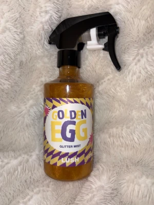 Lush Golden Egg Glitter Mist - Golden Egg Glitter Mist från Lush är en glittrig spray i guld med en söt doft. Kommer i en plastflaska med svart spraymunstycke. Perfekt för att ge huden eller håret en skimrande finish. Helt full!! 