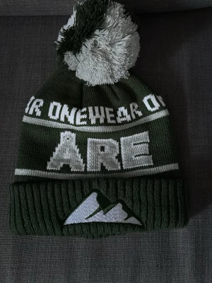 Grön Åre mössa med tofs - Säljer denna Stickad grön'ÅRE' mössan från 'ONEWEAR', då jag inte har användning av den. Mössan är bara testad aldig använde. Så den går bättre nytta åt någon annan därav det priset 