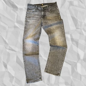 Grå jeansbyxor, 30/30 - Snygga grå jeansbyxor från Lee, modellen West med en klassisk skin/straight passform. Byxorna har en midwaist design och är tillverkade i ett slitstarkt denimtyg. Perfekta för en avslappnad stil. Storlek 30/30, kom gärna med bud!