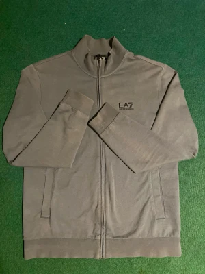 EA7 Emporio Armani Zip - En mycket fin sparsamt använd zip ifrån Emporio Armani. Tröjan har inga defekter förutom en fläck på backsidan som kan kanske kan tvättas bort. Sitter perfekt i storlek!  Priset kan diskuteras💸