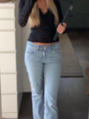 Ljusblå bootcut jeans - Säljer ett par ljusblå bootcut jeans med klassisk femficksdesign och låg midja. Jeansen har utsvängda ben och är tillverkade i denim med en skön passform. Perfekta för en avslappnad och trendig look.