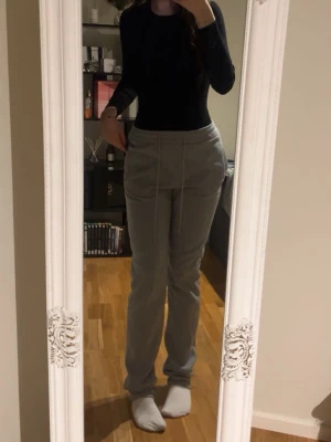 Grå mjukisbyxor med snörning tall - Säljer ett par grå mjukisbyxor med raka ben och elastisk midja med snörning till edition . Byxorna har sidofickor och är gjorda i mjukt bomullsmaterial som är skönt mot huden. Perfekta för chill dagar hemma eller när du vill vara extra bekväm.