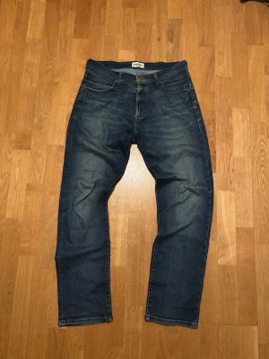 Vintage Wrangler Jeans - Snygga mörkblå jeans med klassisk rak passform och femficksdesign. Jeansen har en enkel look utan slitningar och är perfekta för dig som gillar en tidlös stil. Tillverkade i jeansmaterial med kontrastsömmar.