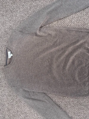 Beige stickad tröja från Hartford - Säljer en stilren beige stickad tröja från Hartford. Tröjan har rund halsringning, långa ärmar och är tillverkad i ett mjukt material som känns skönt mot huden. Perfekt för dig som gillar en enkel och klassisk look.