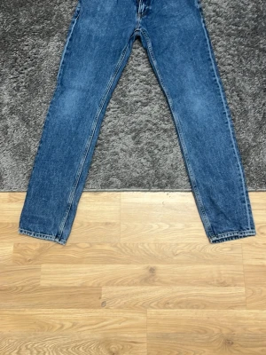 Blå straight jeans från Calvin Klein - Blå jeans från Calvin Klein med klassisk femficksdesign och rak passform. Jeansen har normal midja och tydlig CK-logga på bakre linningen. Tillverkade i slitstarkt denimtyg för en tidlös look. (Pris kan diskuteras)