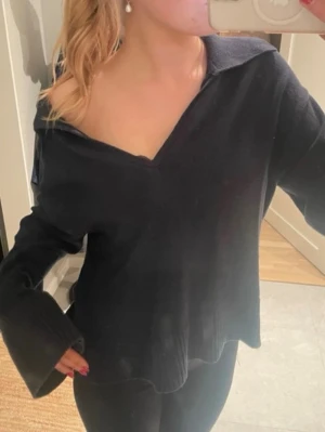 Marinblå stickad tröja Gina Tricot - Trendig blå stickad tröja från Gina Tricot med v-ringad hals och bred krage. Tröjan har långa, vida ärmar och avslappnad passform. Perfekt att styla till jeans eller kjol för en cool look.