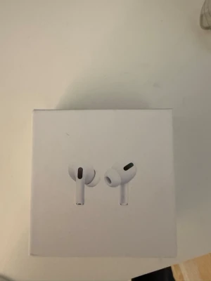 Apple AirPods Pro trådlösa hörlurar - Säljer ett par Apple AirPods Pro, trådlösa in-ear hörlurar i vit färg. Kommer i originalförpackning med stilren design och Apple-logga. Hörlurarna är oanvända 