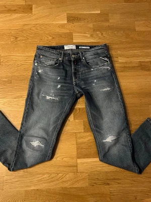 Blå slitna jeans från Replay - Snygga blå jeans från Replay med slitna detaljer och distressed look. Klassisk femficksmodell med raka ben och normal midja. Jeansen är gjorda i denim och har en cool tvättad finish samt Replay-lapp bak i midjan. L29 W30 får väldigt mycket komplimang av grabbarna🙌🏽🙌🏽