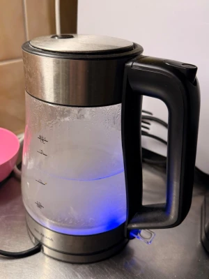 Glasvattenkokare med LED-belysning - Snygg vattenkokare i glas och rostfritt stål från Wilfa. Har svart handtag och lock samt blå LED-belysning när den är igång. Tydliga nivåmarkeringar på sidan och modern design som passar i köket.