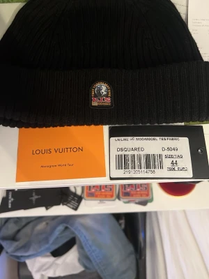 Svart ribbstickad mössa Parajumpers - Snygg svart ribbstickad mössa från Parajumpers med klassisk uppvikt kant och broderad logotyp framtill. Tillverkad i mjukt material som håller dig varm och passar perfekt till streetwear eller casual stil.