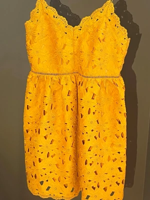 Gul spetsklänning med blommönster - Snygg gul kortklänning med tunna axelband och vacker spets i blommönster. Klänningen har en omlottliknande överdel och dekorativa kanter. Perfekt för sommarens alla tillfällen och ger en fräsch och färgstark look. Använts en gång och köpt från H&M. OBS! Dragkedjan är seg och svår att dra upp, men den går att stänga upp öppna! Måste använda rätta knycken bara✨