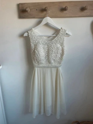 Vit spetsklänning med chiffongkjol - Söt vit klänning med spets upptill och luftig chiffongkjol. Ärmlös modell med rund halsringning och markerad midja. Perfekt för sommarens alla tillfällen. Spetsen ger en romantisk känsla och kjolen faller lätt och fint.