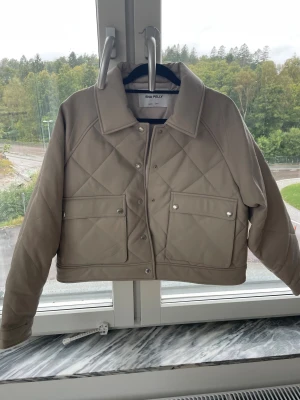 Beige quiltad skinnjacka Ena Pelly - Snygg beige skinnjacka i äkta läder från australiska modemärket Ena Pelly . Modell Loretta quilted jacket, US 6 motsvarande svensk storlek 36. Jackan har en klassisk krage, tryckknappar och raka långa ärmar. Perfekt för dig som gillar stilrena och trendiga jackor med lite edge.