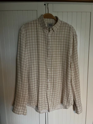 Beige rutig skjorta från Acne - Äldre beige och vit rutig skjorta från Acne Studios. Tillverkad i mjuk bomull. 