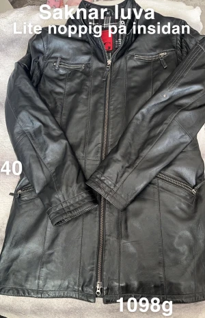 Svart skinnjacka från Vintage Extreme - Svart skinnjacka med coola dragkedjor och fickor fram, fodrad med rutigt tyg i svart, vitt och rött. Jackan har lång ärm och ståkrage, perfekt för dig som gillar en edgy stil. Märke Goldstein of sweden. Snygg passform och detaljerad sömnad.🌸Sparsamt använd. Lätt fodrad. Finns lite noppor på insidan. Saknar luva. Storlek 40 