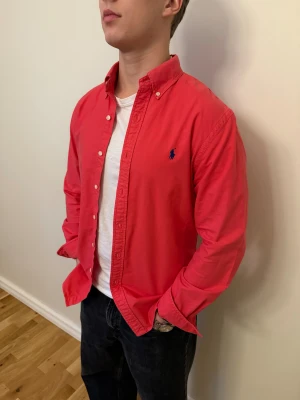 Röd/Rosa Ralph Lauren skjorta  - En snygg polo skjorta som passar till alla tillställningar! Du ska kunna uttrycka stil utan att det kostar för mycket!🕺🍾💼🤩  Storlek👔:  M Nypris💰:  ca 1399 kr
